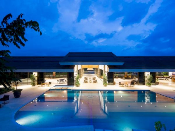 A luxurious outdoor pool area at night, with ambient lighting and elegant architecture under a deep blue sky.